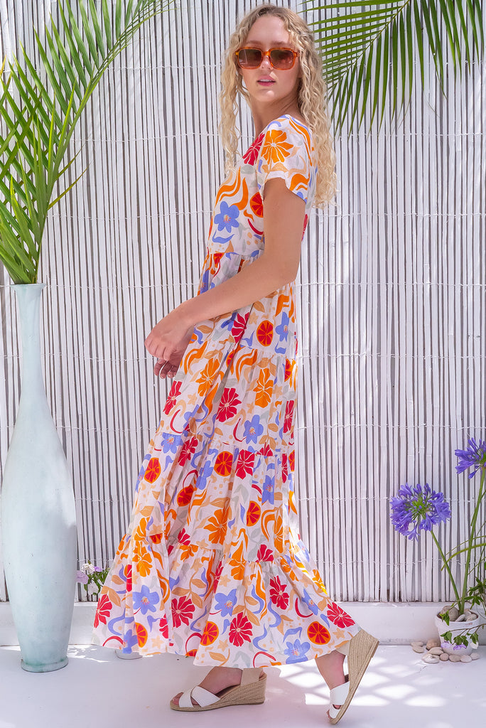 The Lucky Lulu Mediterranean Gold Maxi Dress is a gorgeous cream based maxi dress with a large mediterranean print in shades of orange, red, and periwinkle. This dress features a scooped neckline, adjustable waist tabs, side pockets and a wide tiered skirt. Made from a woven blend of cotton and rayon.