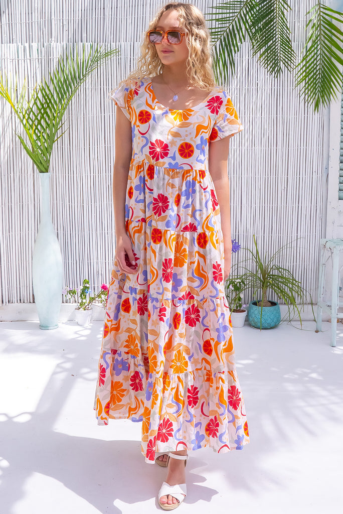 The Lucky Lulu Mediterranean Gold Maxi Dress is a gorgeous cream based maxi dress with a large mediterranean print in shades of orange, red, and periwinkle. This dress features a scooped neckline, adjustable waist tabs, side pockets and a wide tiered skirt. Made from a woven blend of cotton and rayon.