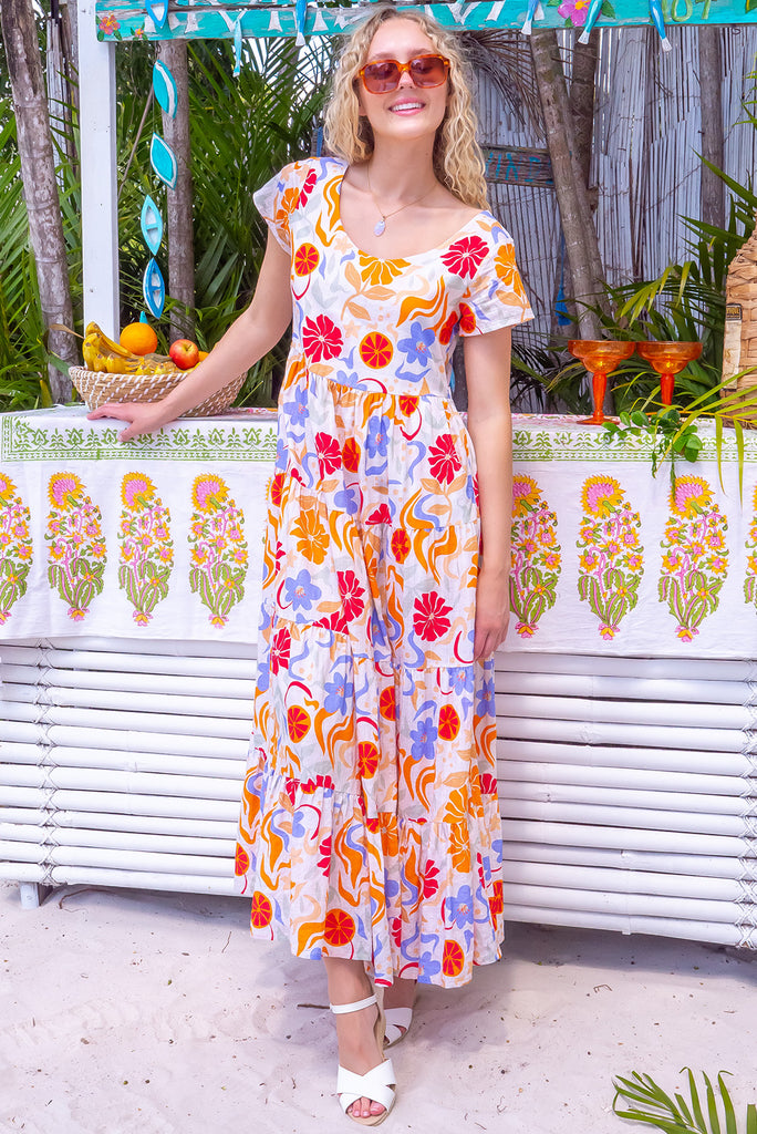 The Lucky Lulu Mediterranean Gold Maxi Dress is a gorgeous cream based maxi dress with a large mediterranean print in shades of orange, red, and periwinkle. This dress features a scooped neckline, adjustable waist tabs, side pockets and a wide tiered skirt. Made from a woven blend of cotton and rayon.