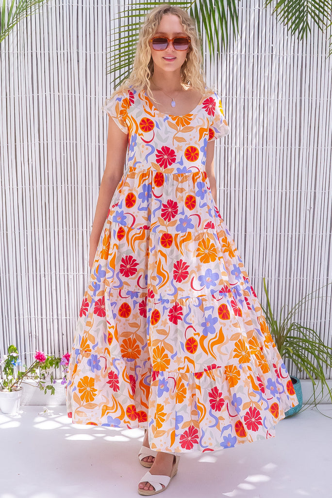 The Lucky Lulu Mediterranean Gold Maxi Dress is a gorgeous cream based maxi dress with a large mediterranean print in shades of orange, red, and periwinkle. This dress features a scooped neckline, adjustable waist tabs, side pockets and a wide tiered skirt. Made from a woven blend of cotton and rayon.