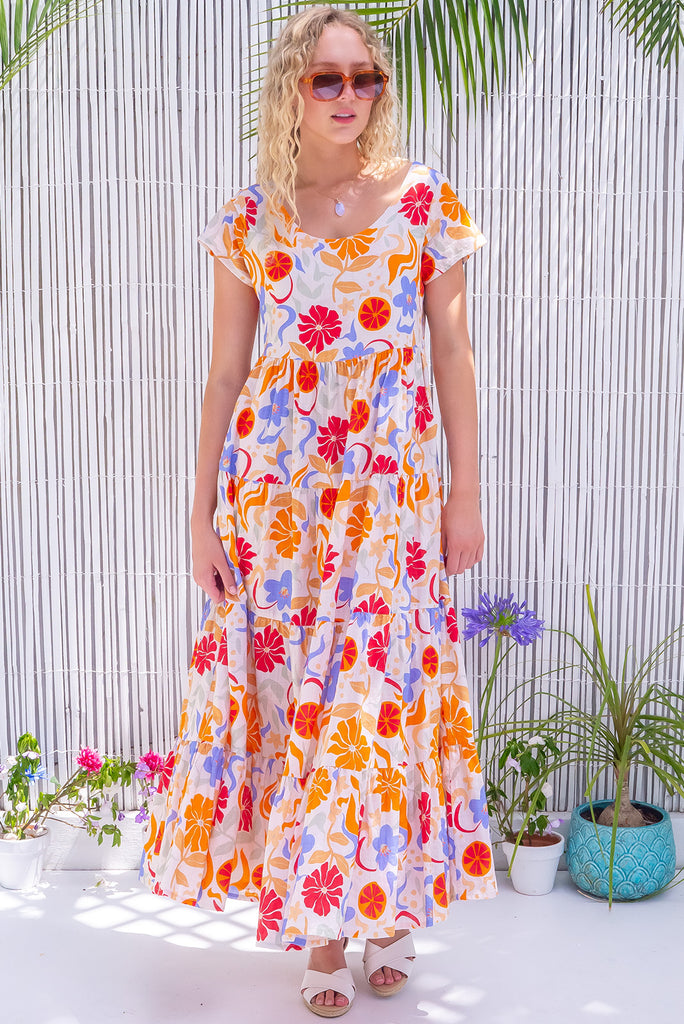 The Lucky Lulu Mediterranean Gold Maxi Dress is a gorgeous cream based maxi dress with a large mediterranean print in shades of orange, red, and periwinkle. This dress features a scooped neckline, adjustable waist tabs, side pockets and a wide tiered skirt. Made from a woven blend of cotton and rayon.
