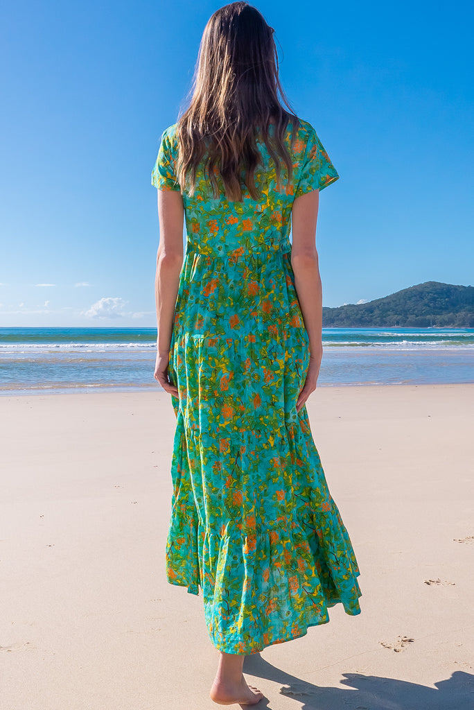 The Lucky Lulu Summer Blue Maxi Dress is a beautiful tiered maxi dress with a blue base and a green botanical print. This dress features a scooped neckline, adjustable waist tabs, side pockets and a wide tiered skirt. Made a woven blend of cotton and rayon.