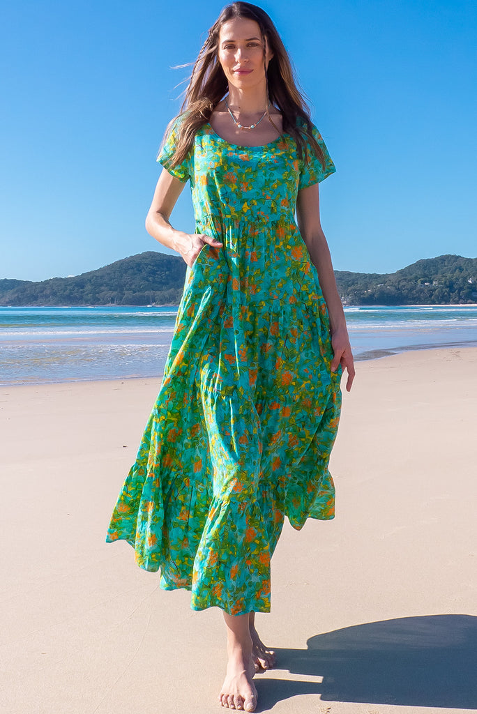 The Lucky Lulu Summer Blue Maxi Dress is a beautiful tiered maxi dress with a blue base and a green botanical print. This dress features a scooped neckline, adjustable waist tabs, side pockets and a wide tiered skirt. Made a woven blend of cotton and rayon.
