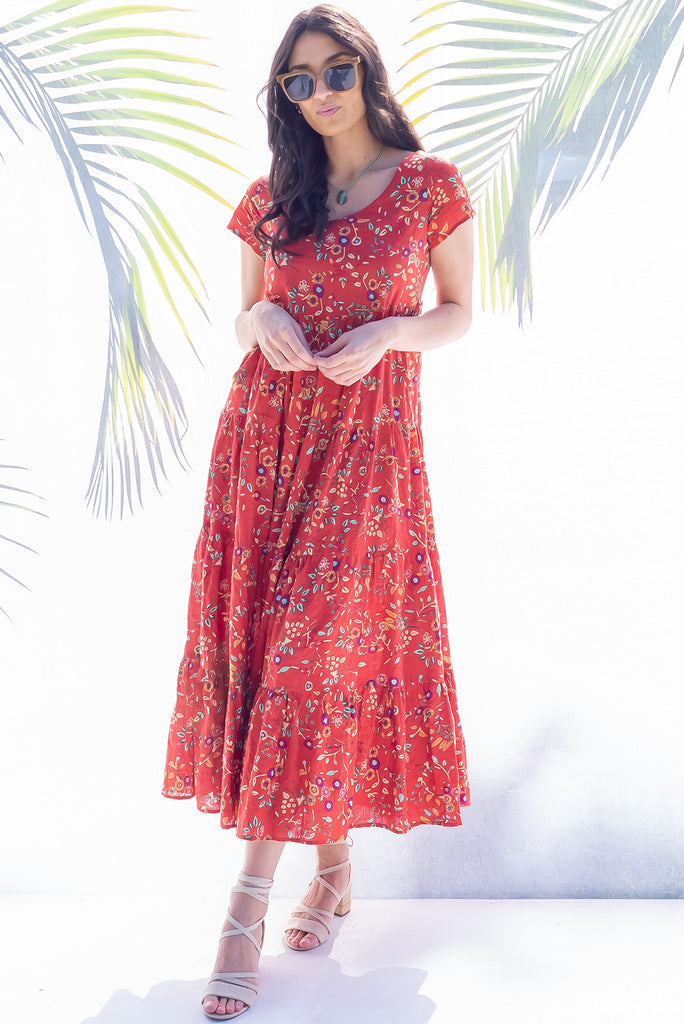 The Lucky Lulu Umbria Maxi Dress is a beautiful tiered maxi dress with a terracotta base and a floral leaf print. This dress features a scooped neckline, adjustable waist tabs, side pockets and a wide tiered skirt. Made a woven blend of cotton and rayon.