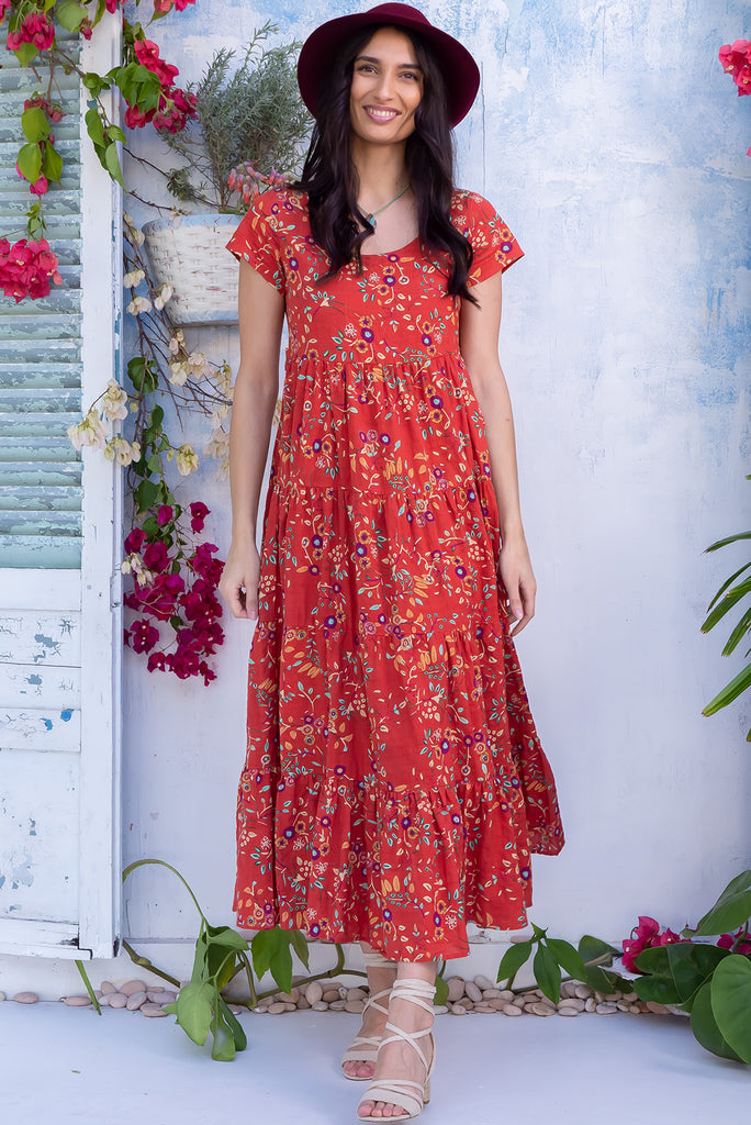 The Lucky Lulu Umbria Maxi Dress is a beautiful tiered maxi dress with a terracotta base and a floral leaf print. This dress features a scooped neckline, adjustable waist tabs, side pockets and a wide tiered skirt. Made a woven blend of cotton and rayon.