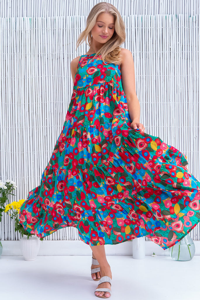 The Lulu Darling Green Floral Maxi Dress is a gorgeous green dress with a bright, multicoloured abstract floral print. The maxi dress features a high neck, high cut under the arms, full tiered skirt falling from under bust, side pockets, and is woven cotton/rayon blend. 