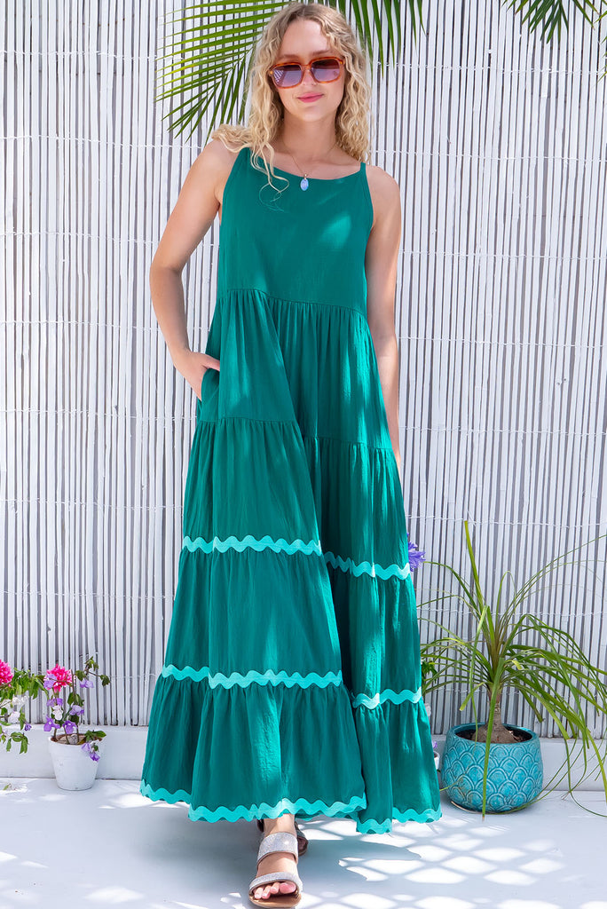 The Lulu Ric Rac Jade Maxi Dress is a gorgeous jade green maxi dress with a pastel green oversized ric-rac braid feature. The maxi dress features a high neck, high cut under the arms, full tiered skirt falling from under bust, ric-rac on bottom three tiers, side pockets, and is made from woven cotton. 