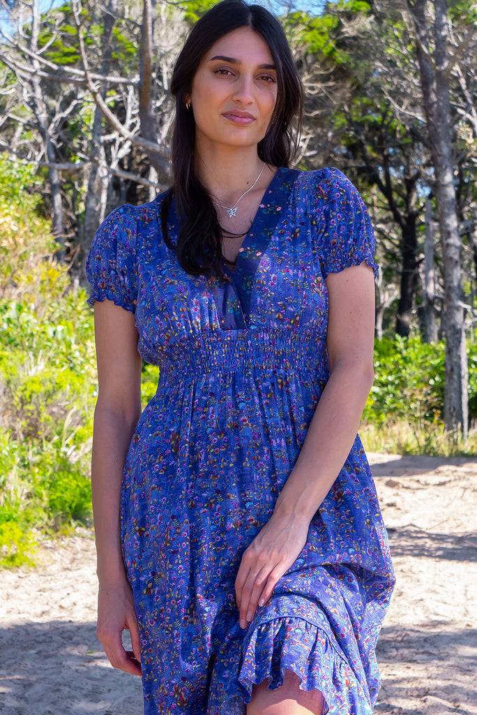 The Moonshadow Blur Maxi Dress is a beautiful periwinkle blue based dress with a floral print. The dress features a mixed print on the neckline panel, short sleeves, v-neckline with hidden bust fastening, elasticated empire line, tie at the back of the neck, and side pockets. Made from a woven blend of cotton and rayon.
