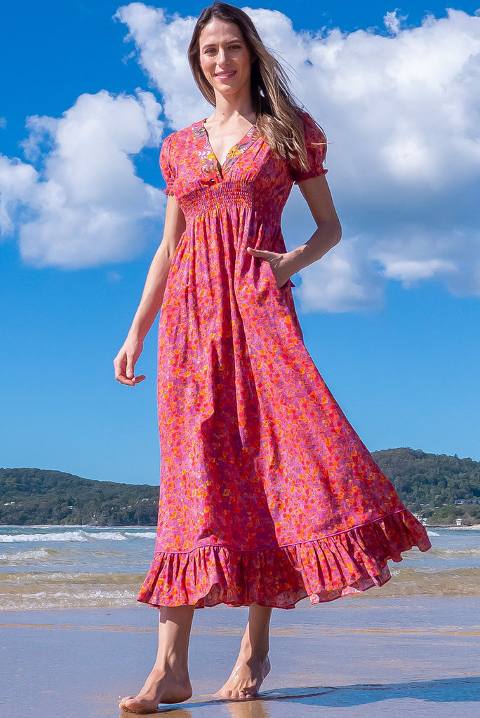 The Moonshadow Pink Spice Maxi Dress is a gorgeous pink based dress with a floral print. The dress features a mixed print on the neckline panel, short sleeves, v-neckline with hidden bust fastening, elasticated empire line, tie at the back of the neck, and side pockets. Made from a woven blend of cotton and rayon.
