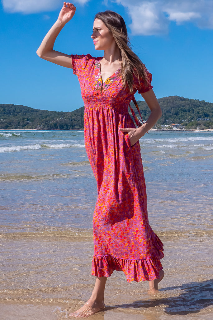 The Moonshadow Pink Spice Maxi Dress is a gorgeous pink based dress with a floral print. The dress features a mixed print on the neckline panel, short sleeves, v-neckline with hidden bust fastening, elasticated empire line, tie at the back of the neck, and side pockets. Made from a woven blend of cotton and rayon.