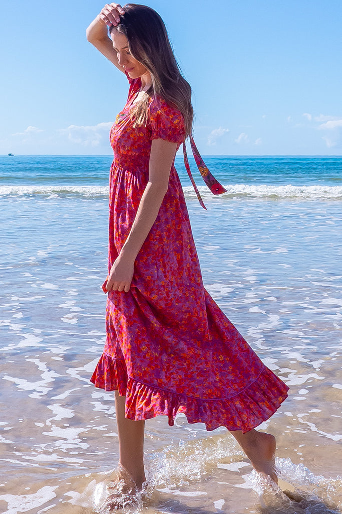 The Moonshadow Pink Spice Maxi Dress is a gorgeous pink based dress with a floral print. The dress features a mixed print on the neckline panel, short sleeves, v-neckline with hidden bust fastening, elasticated empire line, tie at the back of the neck, and side pockets. Made from a woven blend of cotton and rayon.