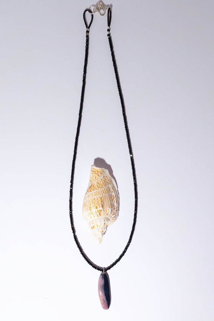 Discover the magic of Australian Black Opals. This incredibly chic necklace features a mesmerising organic cut opal with brilliant red, pink &amp; gold colour play.