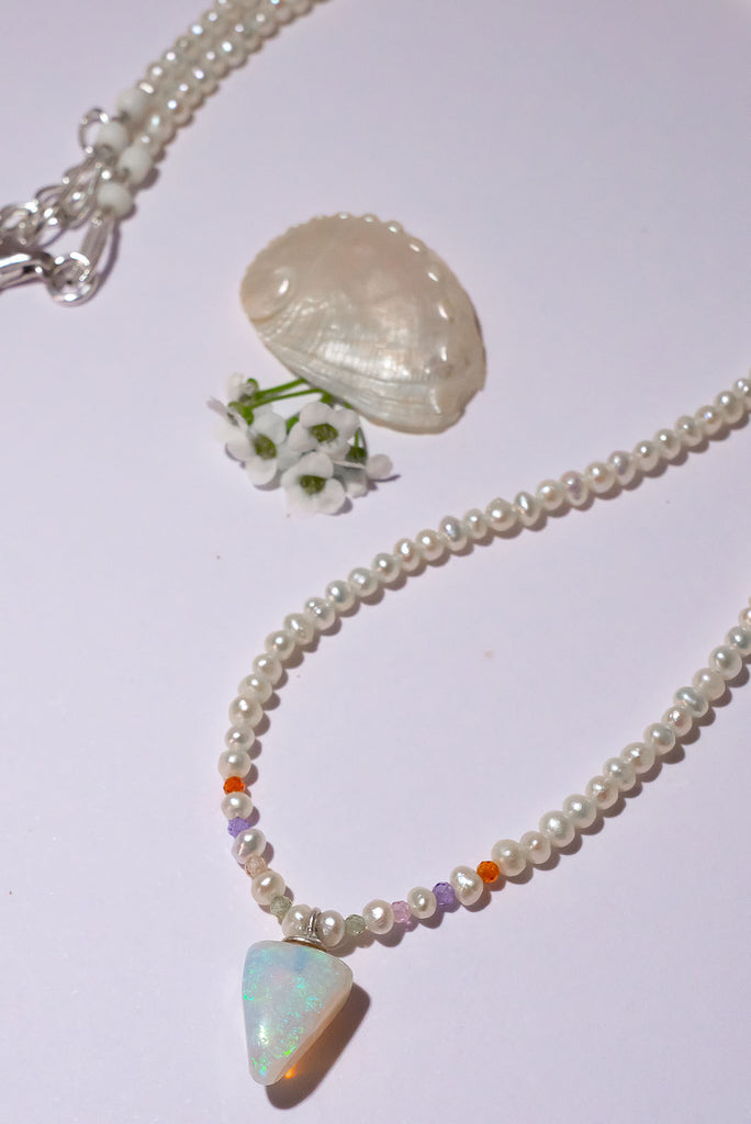 A pearl necklace with twist, we have added a tiny luminous crystal opal as the centrepiece.