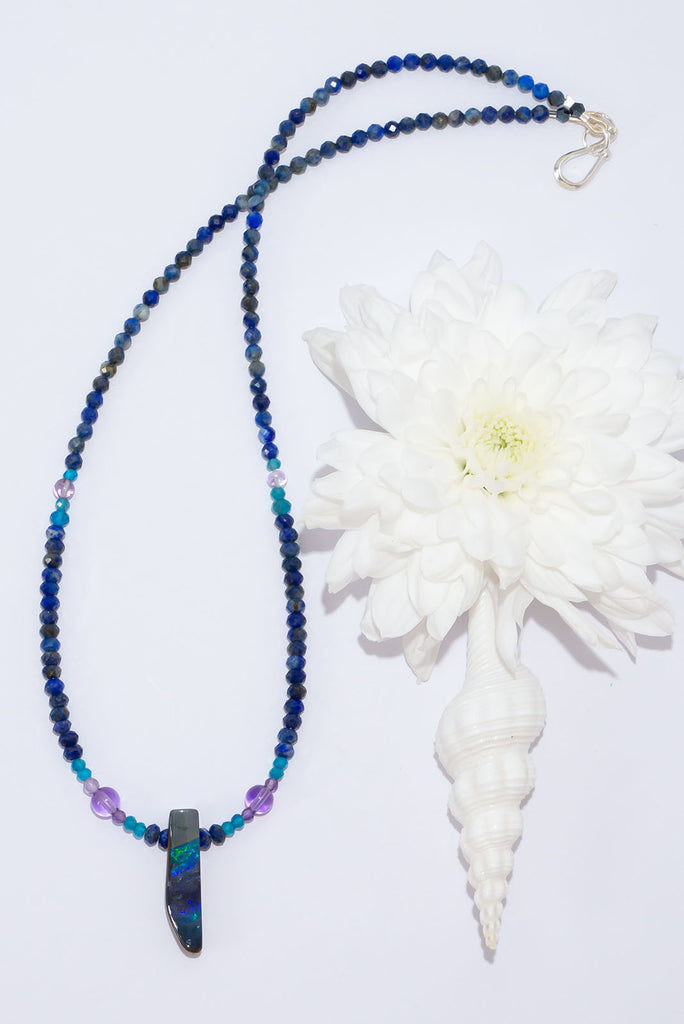 The wind passes over the outback in a streak of of blue, and a rolling flash of green. A solid opal with the intensity of bright colour that is absolutely unique, on a deep blue Lapis Lazuli faceted bead necklace.