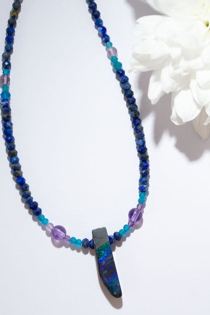 The wind passes over the outback in a streak of of blue, and a rolling flash of green. A solid opal with the intensity of bright colour that is absolutely unique, on a deep blue Lapis Lazuli faceted bead necklace.