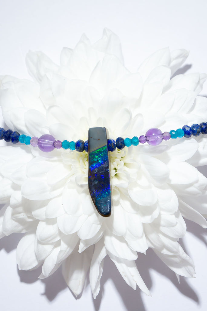 The wind passes over the outback in a streak of of blue, and a rolling flash of green. A solid opal with the intensity of bright colour that is absolutely unique, on a deep blue Lapis Lazuli faceted bead necklace.