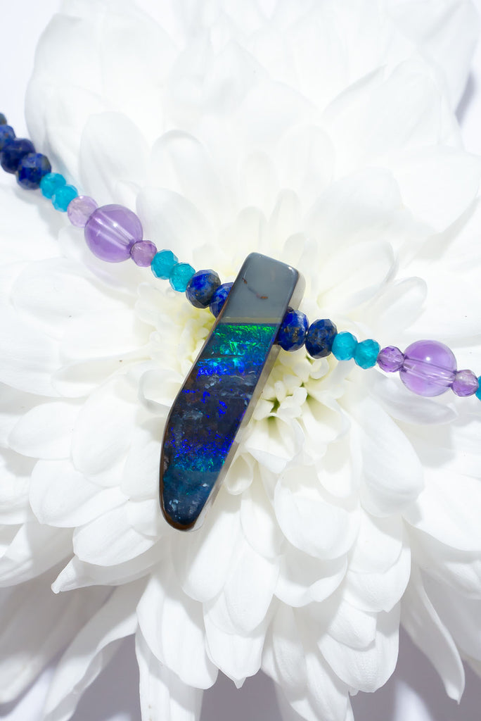 The wind passes over the outback in a streak of of blue, and a rolling flash of green. A solid opal with the intensity of bright colour that is absolutely unique, on a deep blue Lapis Lazuli faceted bead necklace.