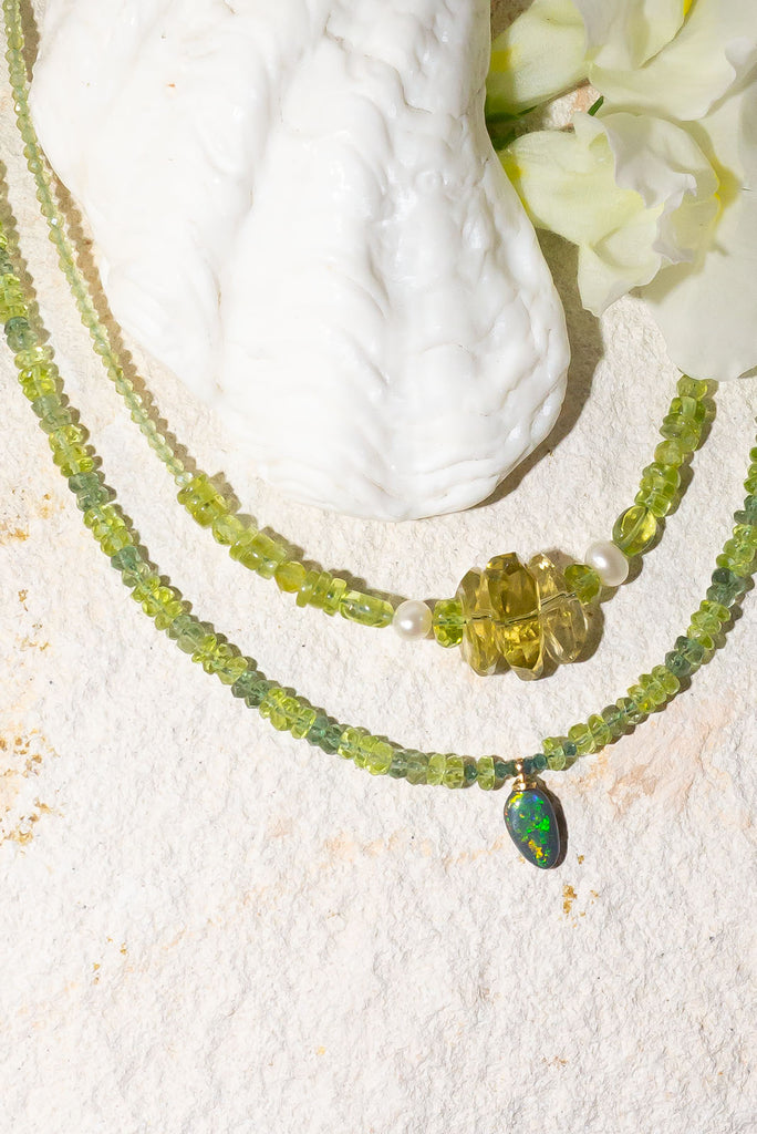Complimented by gorgeous green gemstones this sparkling black Lightning Ridge opal is something very special.