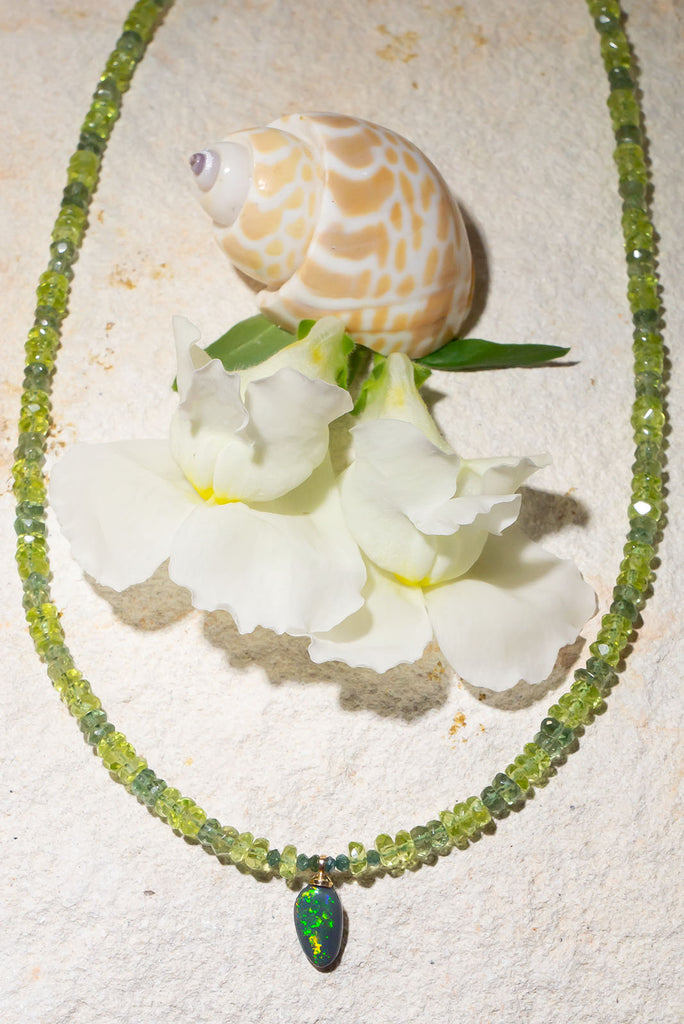 Complimented by gorgeous green gemstones this sparkling black Lightning Ridge opal is something very special.