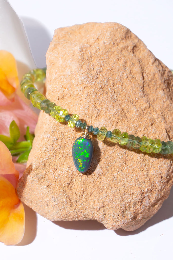 Complimented by gorgeous green gemstones this sparkling black Lightning Ridge opal is something very special.