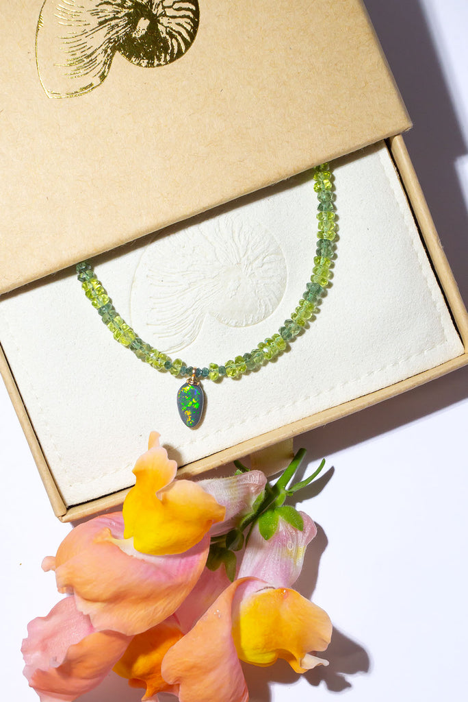 Complimented by gorgeous green gemstones this sparkling black Lightning Ridge opal is something very special.