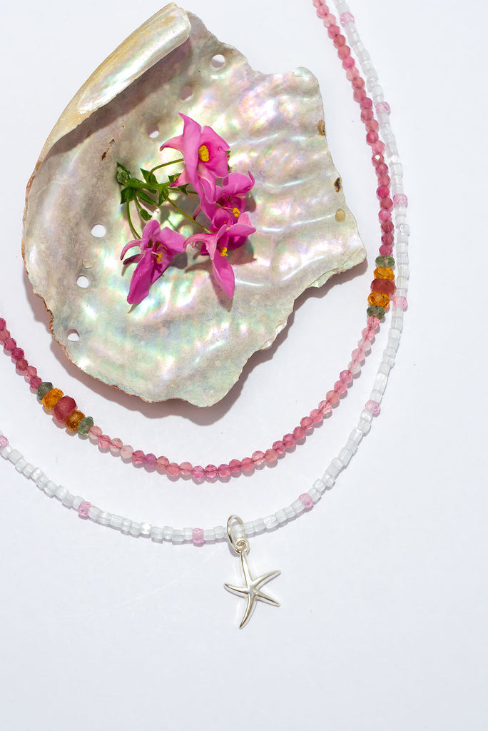 A shimmering arctic white delight. This delicate stand of luminescent features an enchanting sterling silver starfish pendant.