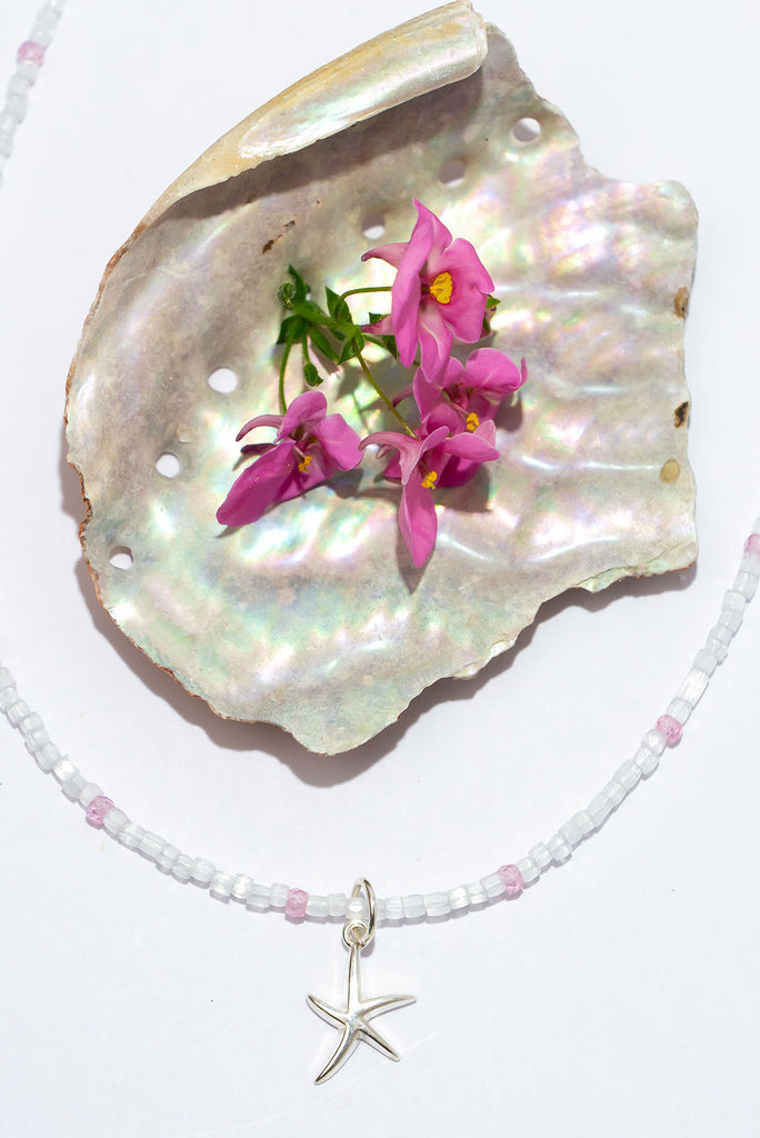 A shimmering arctic white delight. This delicate stand of luminescent features an enchanting sterling silver starfish pendant.