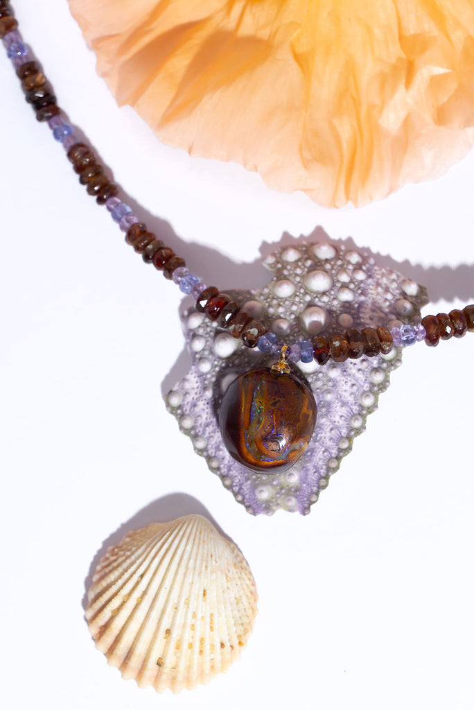 Like the meeting of a bright night sky and deep red earth the usual combination of Tasmanian red zircon and Tanzanite are a beautiful reflection of the colours in this necklaces Australian boulder opal pendant.