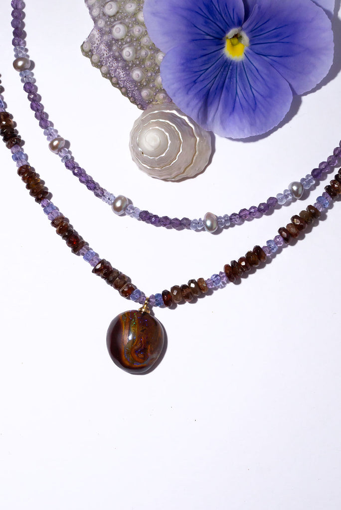 Like the meeting of a bright night sky and deep red earth the usual combination of Tasmanian red zircon and Tanzanite are a beautiful reflection of the colours in this necklaces Australian boulder opal pendant.