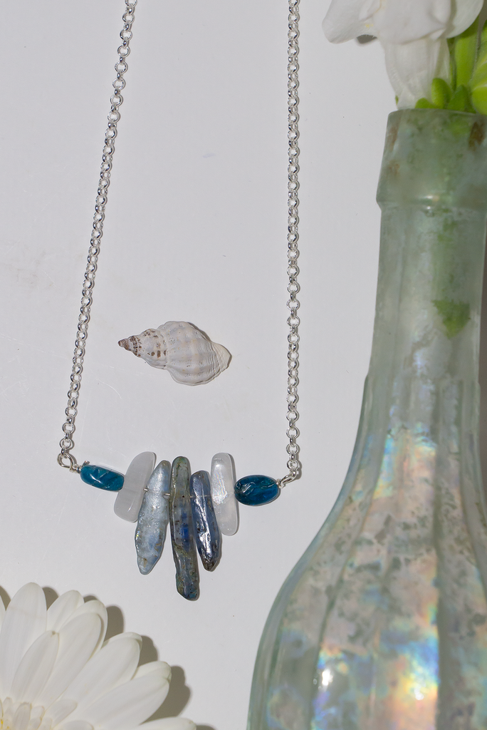 The swing style necklace is designed in a simple and chic style, using rough shards of the semi precious stone Kyanite.