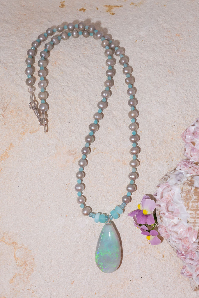 Like the colour of a wave as it turns, a crystal opal with tiny sparkle flashes of green and blue, on a necklace of small lustrous silver grey pearls with Amazonite highlights.