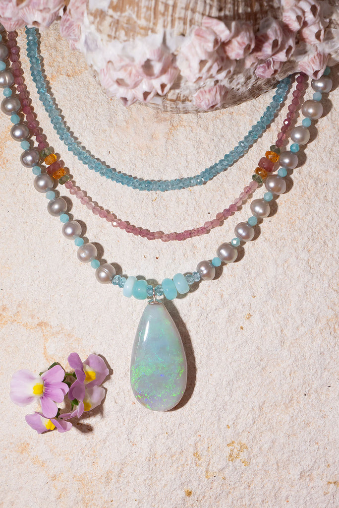 Like the colour of a wave as it turns, a crystal opal with tiny sparkle flashes of green and blue, on a necklace of small lustrous silver grey pearls with Amazonite highlights.