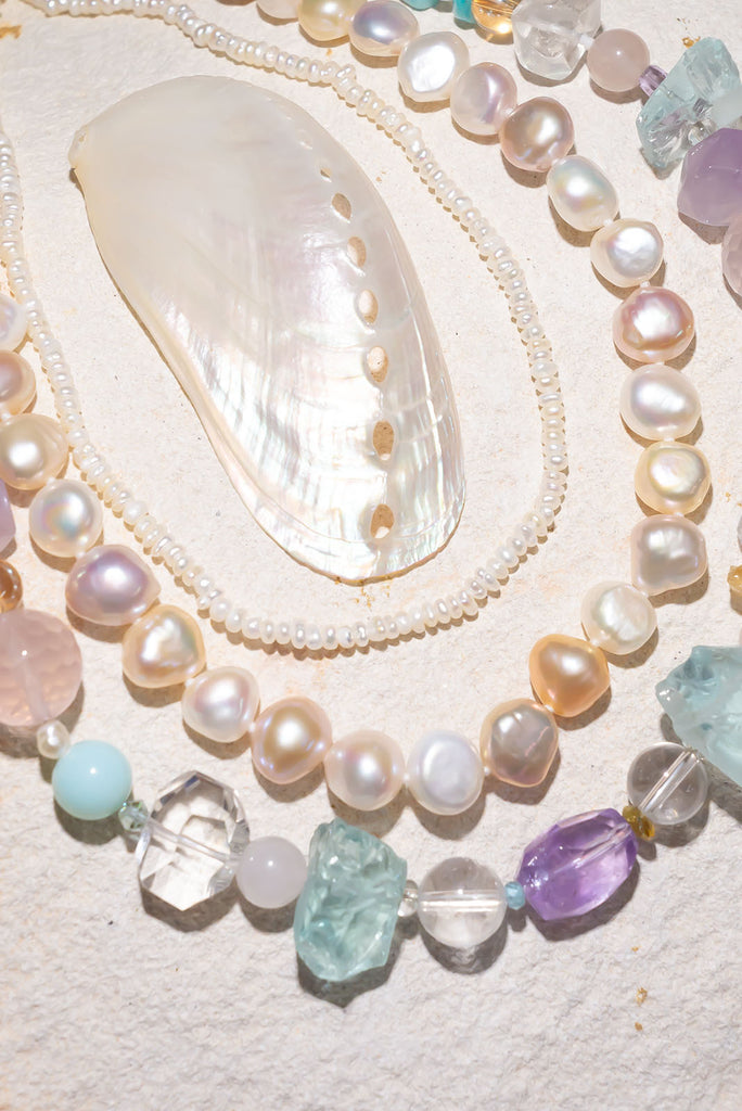 Necklace with pearls and gemstones on a textured surface