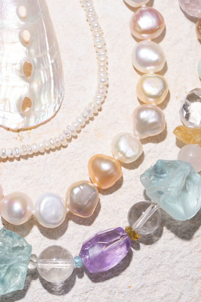 Close-up of pearl and gemstone necklaces on a light background