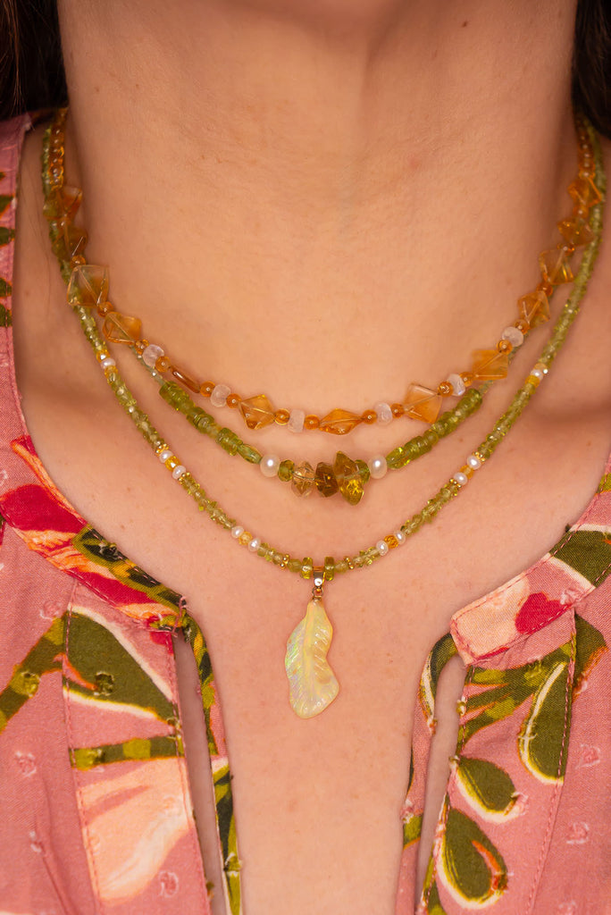 Feel the magic of this beautiful crystal opal carved into a feather, glowing green, blue, pink and gold this ethereal piece comes on a necklace of soft green Peridot beads with Citrine and pearl highlights.