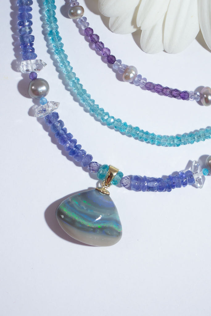 Misty grey, sparkling green, blue and gold rivers that dip and swirl across the opal, an enchanting Australian opal strung on a gorgeous Tanzanite gemstone necklace highlighted with soft grey pearls.