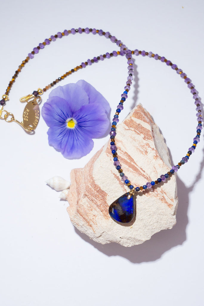 With beautiful pools of dark blue colour play found within the deep brown boulder stone this enthralling opal is complimented by the jewel tones of amethyst, lapis lazuli & shimmering tigers eye.