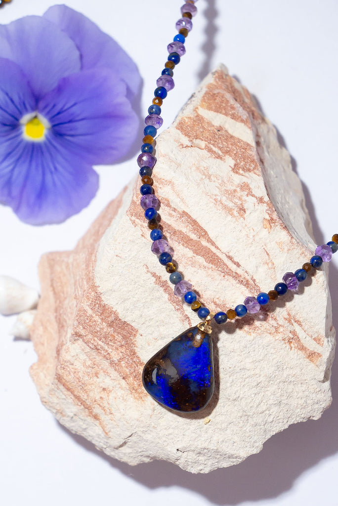 With beautiful pools of dark blue colour play found within the deep brown boulder stone this enthralling opal is complimented by the jewel tones of amethyst, lapis lazuli & shimmering tigers eye.