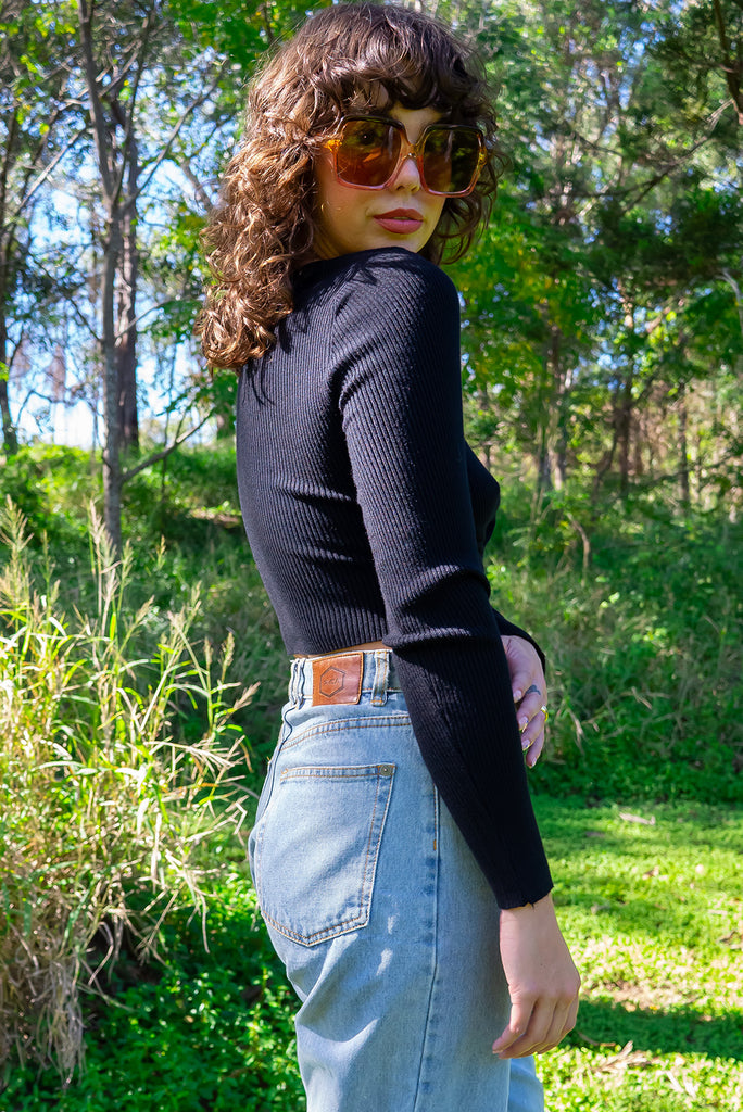 The Olivia Noir Long Sleeve Shirt is a black knit top with a twist feature on the hem. Made from viscose and nylon.