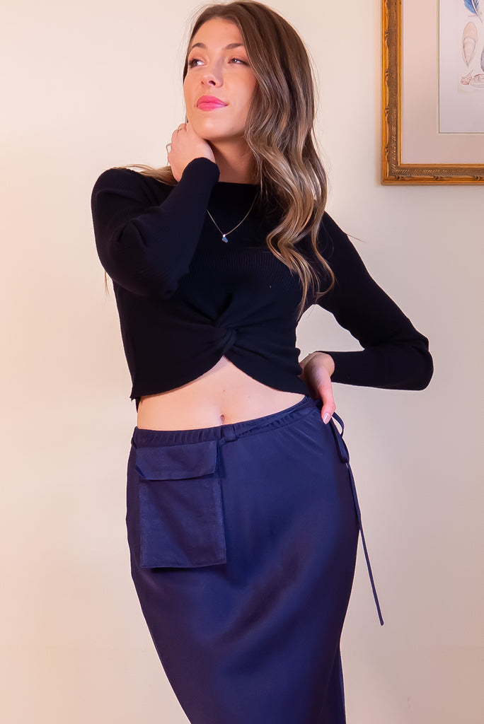 The Olivia Noir Long Sleeve Shirt is a black knit top with a twist feature on the hem. Made from viscose and nylon.
