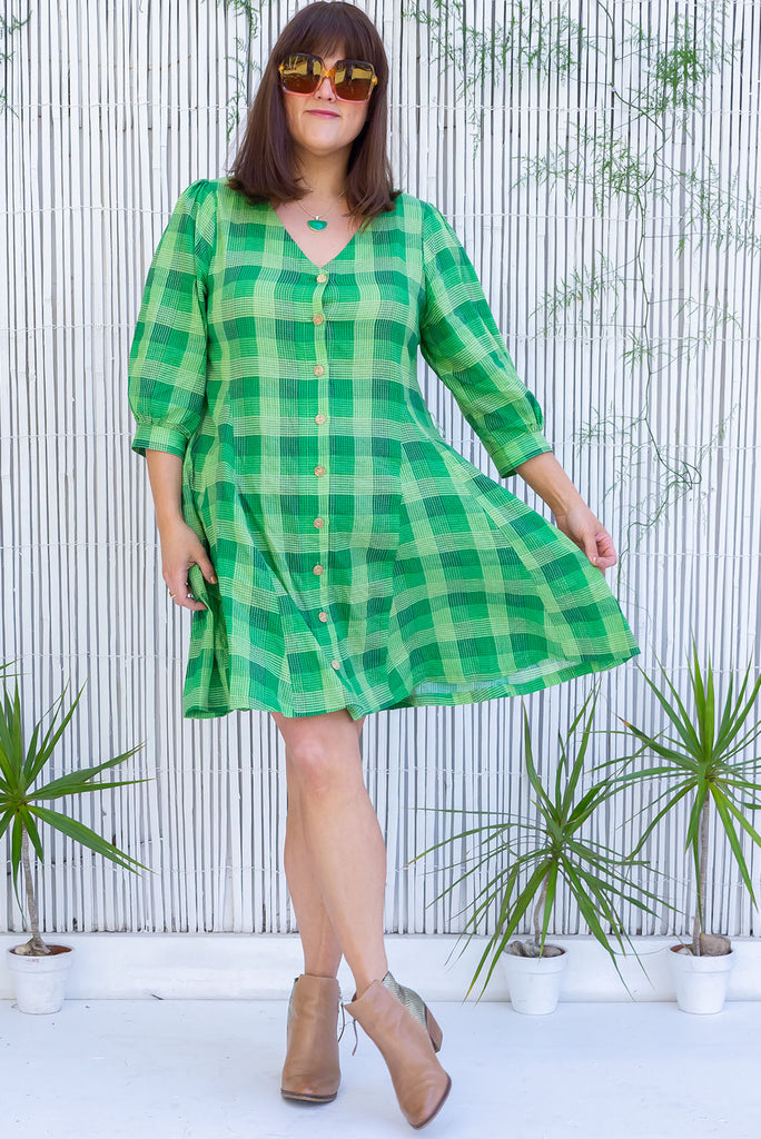 The Orbit Groovy Green Dress is a gorgeous lime green plaid printed dress. The mini dress features a v-neckline, functional buttons from the chest to hemline, cuffed 3/4 sleeves, paneling in the skirting, belt loops with a wide waist tie, and side pockets. Made from a woven blend of cotton and rayon.