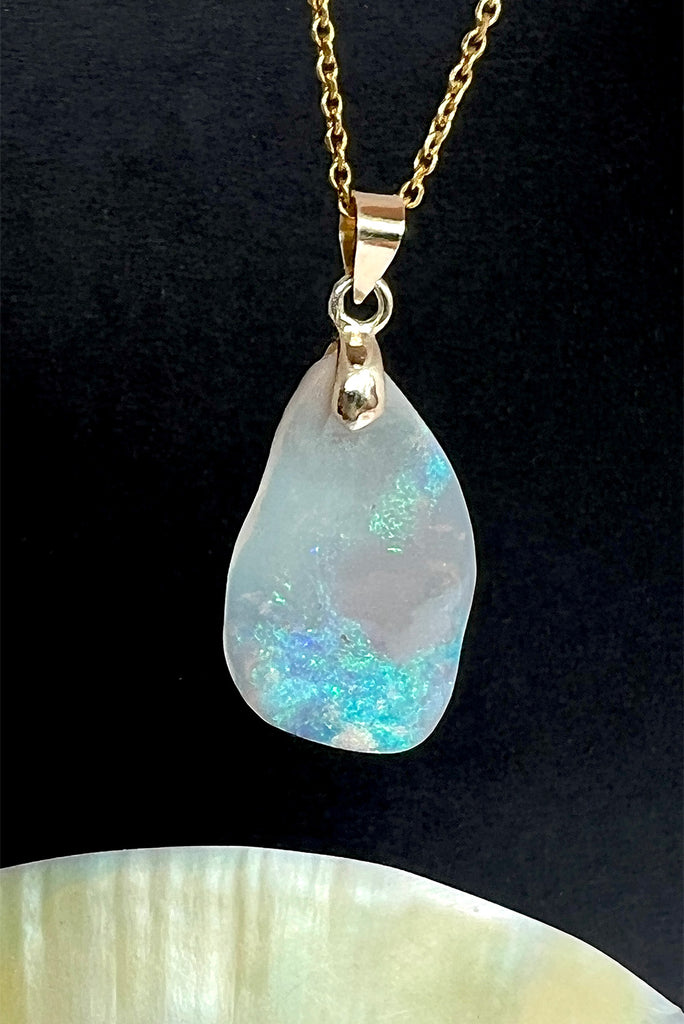 An absolutely stunning opal pendant featuring a soft sliver of Australian crystal opal cut and polished to show the wonderful colour that reveals itself underneath. The top of the stone is pale misty mauve, the base has bright flashes of green, blue and pinky orange. A rare one of a kind opal cut freeform with a highly polished undulating surface.