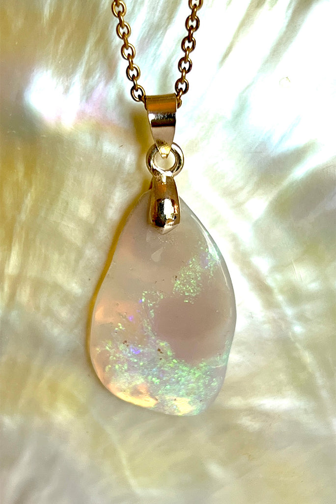 An absolutely stunning opal pendant featuring a soft sliver of Australian crystal opal cut and polished to show the wonderful colour that reveals itself underneath. The top of the stone is pale misty mauve, the base has bright flashes of green, blue and pinky orange. A rare one of a kind opal cut freeform with a highly polished undulating surface.