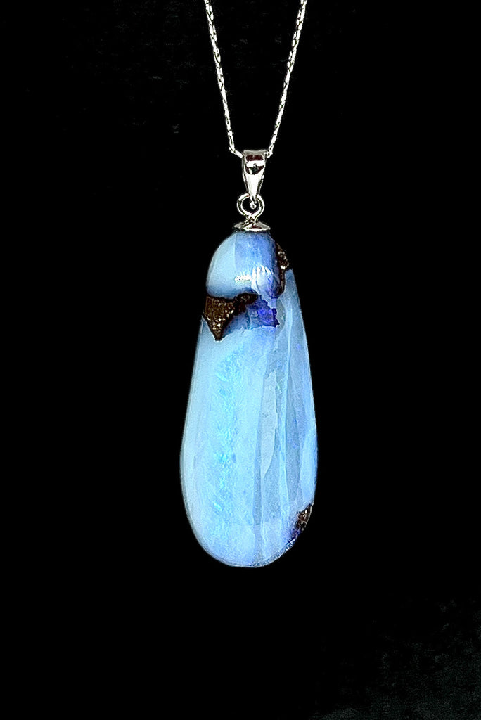 An Australian solid boulder opal pendant shaped into a droplet shape, with crystalline detail that reveals flashes of blue and mauve.