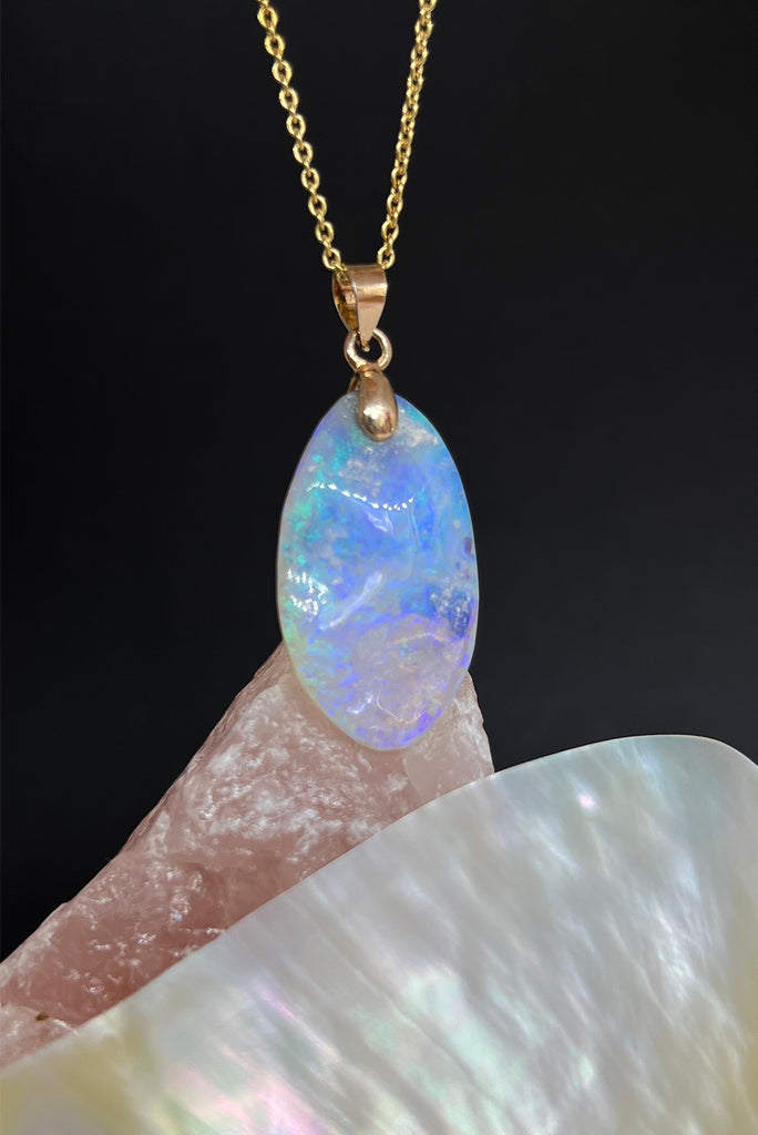 An opal pendant featuring a freeform droplet of Australian crystal opal cut and polished to reveal the pretty flecks of colour and sand through the stone. A one of a kind opal.