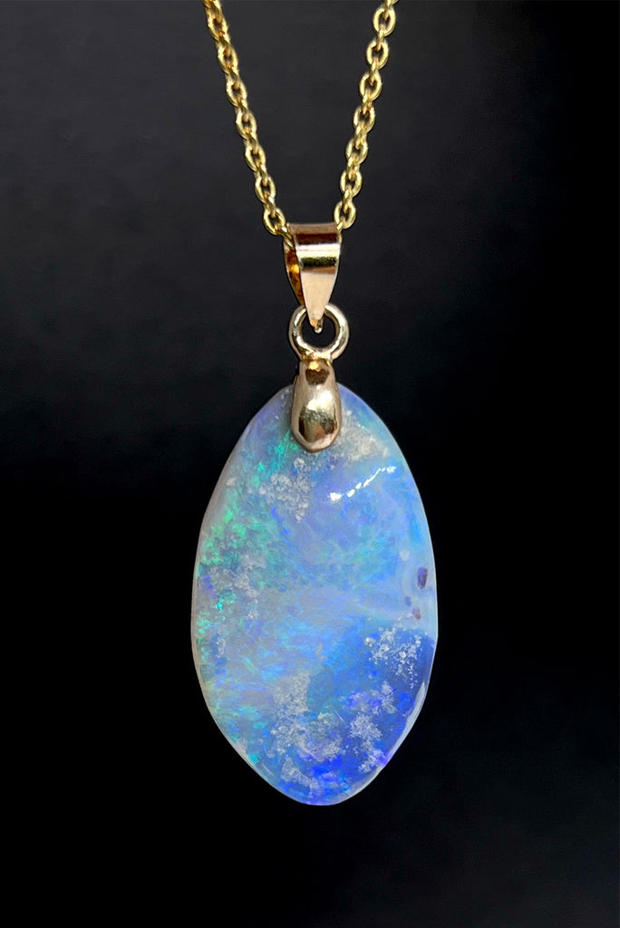 An opal pendant featuring a freeform droplet of Australian crystal opal cut and polished to reveal the pretty flecks of colour and sand through the stone. A one of a kind opal.