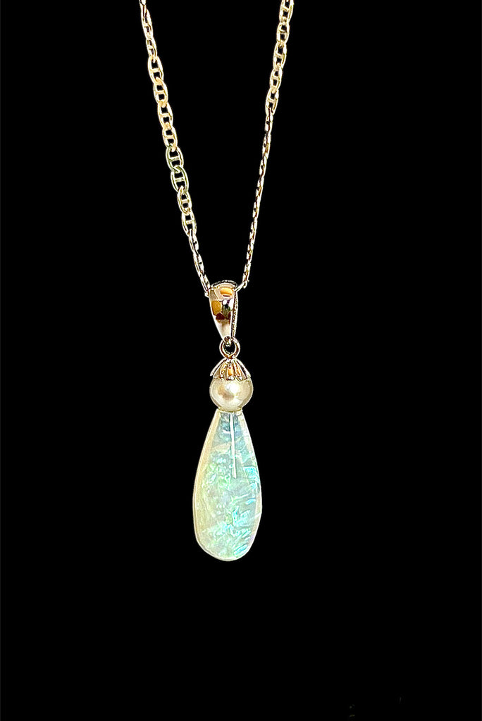 An opal pendant featuring a droplet of Australian crystal opal cut and polished to reveal the flecks of colour through the stone. A one of a kind opal. This piece has soft mystical colouring, flecks of green, blue and mauve.