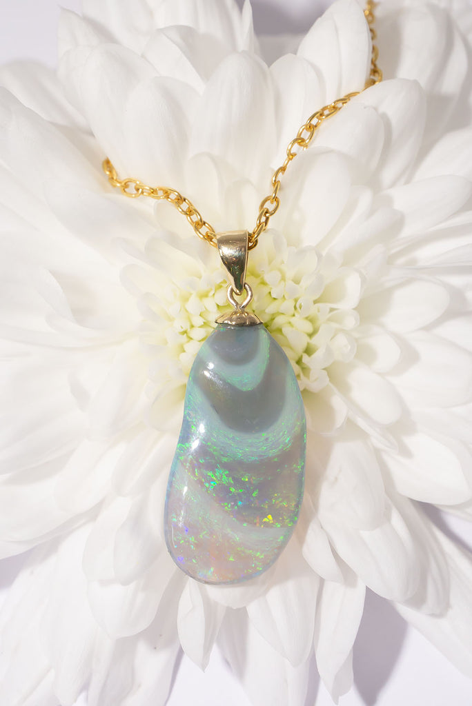 A stunning opal pendant with swirling waves of bright green, mauve and blue, the swirls accented with some gentle hand carving to highlight the swell.