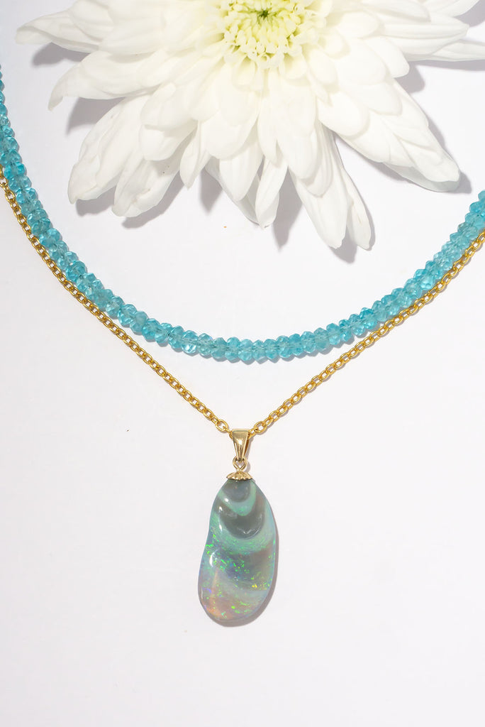 A stunning opal pendant with swirling waves of bright green, mauve and blue, the swirls accented with some gentle hand carving to highlight the swell.
