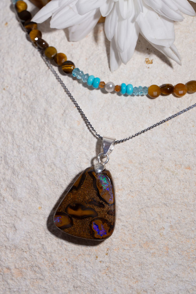 An Australian opal pendant with all the colours of the outback and three bright ponds of mauve and green rising through the stone.